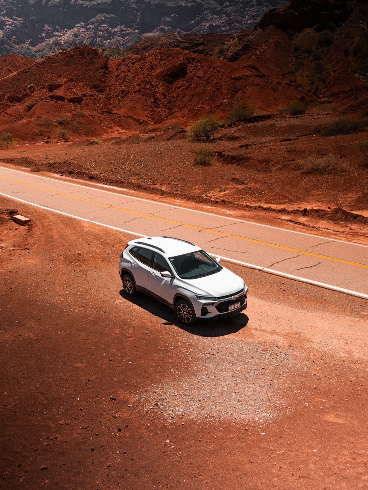 Chevrolet Tracker blanco sobre una ruta entre cerros rojos